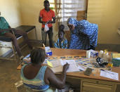 A boy sits in a chair and speaks to a nurse at a small clinic in Gampela village on the outskirts of Burkina Faso's capital, Ouagadougou on Saturday Oct. 10, 2020. The public health clinic responsible for serving approximately 11,000 people, did not have a working fridge for almost a year. The vaccine cold chain hurdle is just the latest disparity of the pandemic weighted against the poor, who more often live and work in crowded conditions that allow the virus to spread, have little access to medical oxygen vital to COVID-19 treatment, and whose health systems lack labs, supplies or technicians to carry out large-scale testing. (AP Photo/Sam Mednick)