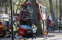 A members of the emergency services walks in front of a bus which crashed into a tree in Kennington, south London, December 20, 2013. 23 people were injured, two seriously, in the crash according to the Metropolitan Police. REUTERS/Suzanne Plunkett (BRITAIN - Tags: DISASTER TRANSPORT)