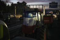 A French flag sits on a tractor at a highway barricade in Aix-en-Provence, southern France, Tuesday, Jan. 30, 2024. France's protesting farmers encircled Paris with traffic-snarling barricades Monday, using hundreds of lumbering tractors and mounds of hay bales to block highways leading to France's capital to pressure the government over the future of their industry. (AP Photo/Daniel Cole)