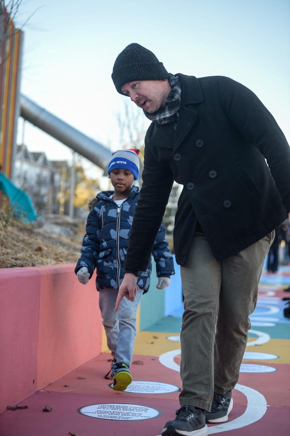 Muralist Dustin Durham, the artist who created Fort Kid's interactive sidewalk mural, shows Samarion Leatherwood, 5, the new installation in Knoxville, Nov. 29, 2023.