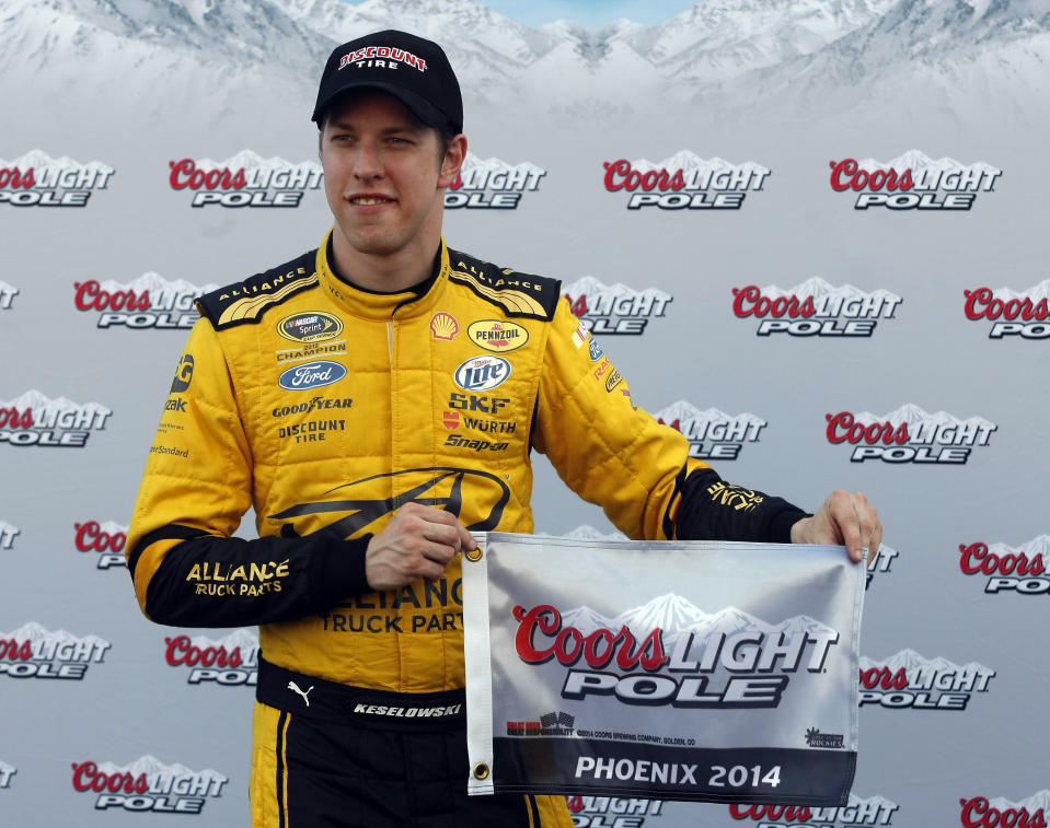 Brad Keselowski holds the flag after winning the pole for Sunday's NASCAR Sprint Cup Series auto race, Friday, Feb. 28, 2014, in Avondale, Ariz. (AP Photo/Rick Scuteri)