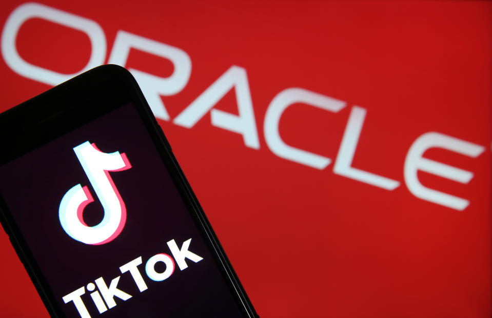 In this photo illustration the logo of Chinese media app for creating and sharing short videos TikTok, also known as Douyin is displayed on the screen of a smartphone in front of a TV screen displaying an Oracle logo on September 15, 2020 in Paris, France. Photo: Chesnot/Getty Images