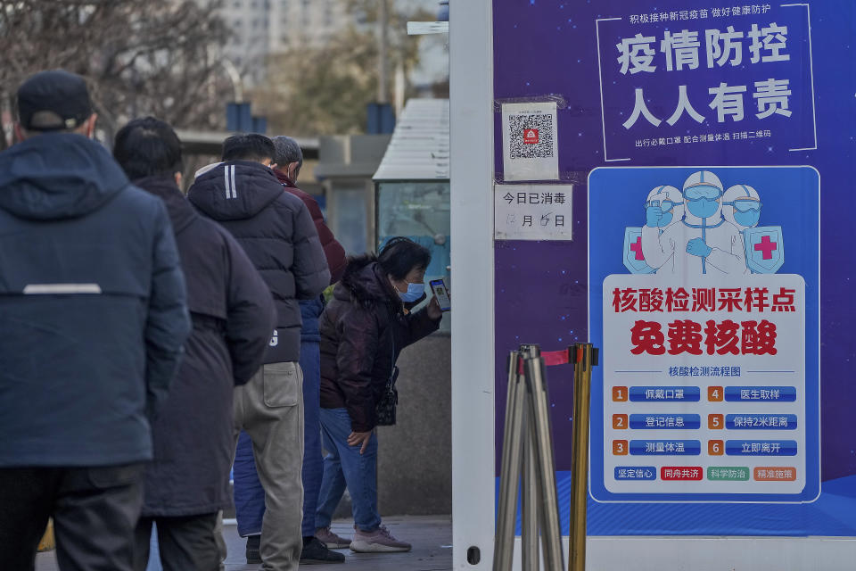 A woman shows her health check QR code as residents line up to get their routine COVID-19 throat swabs at a coronavirus testing site although authorities start easing some of the anti-virus controls in Beijing, Wednesday, Dec. 7, 2022. China has announced new measures rolling back COVID-19 restrictions, including limiting lockdowns and testing requirements. (AP Photo/Andy Wong)