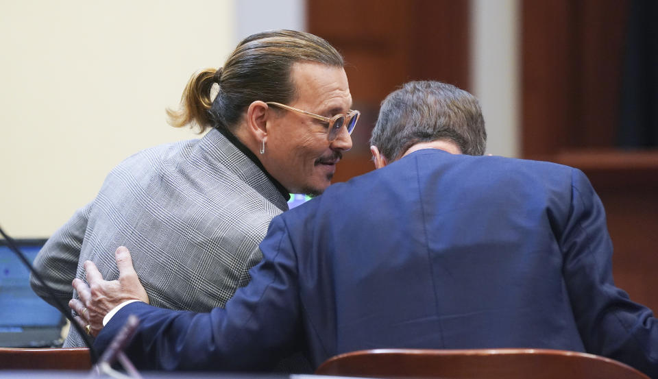 El actor Johnny Depp habla con un miembro de su equipo legal en el Tribunal de Circuito del Condado de Fairfax, el jueves 19 de mayo de 2022 en Fairfax, Virginia. (Shawn Thew/Pool Photo via AP)