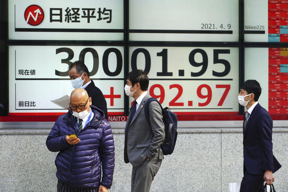 People wearing protective masks stand in front of an electronic stock board showing Japan's Nikkei 225 index at a securities firm in Tokyo Friday, April 9, 2021. Shares fell Friday in most Asian markets after China reported a stronger than expected rise in prices that could prompt authorities to act to cool inflation. (AP Photo/Eugene Hoshiko)