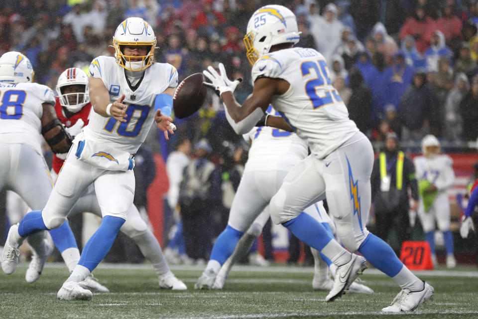 Los Angeles Chargers quarterback Justin Herbert (10) tosses the ball to running back Joshua Kelley (25) during the second half of an NFL football game against the New England Patriots, Sunday, Dec. 3, 2023, in Foxborough, Mass. (AP Photo/Michael Dwyer)