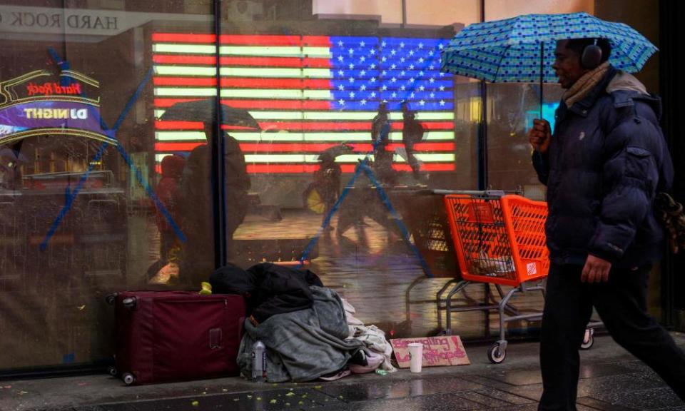 Une personne utilisant un parapluie passe devant un sans-abri à New York.