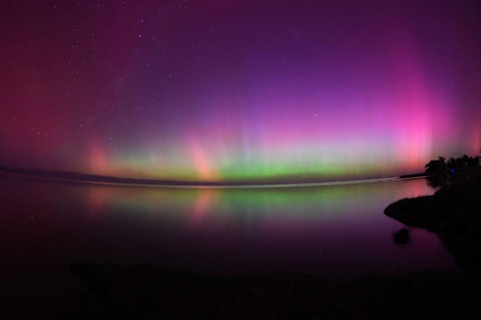 The Aurora Australis, also known as the Southern Lights, glow on the horizon over waters of Lake Ellesmere on the outskirts of Christchurch on May 11, 2024. <em>Photo: Sanka Vidanagama / AFP, SANKA VIDANAGAMA/AFP via Getty Images</em>