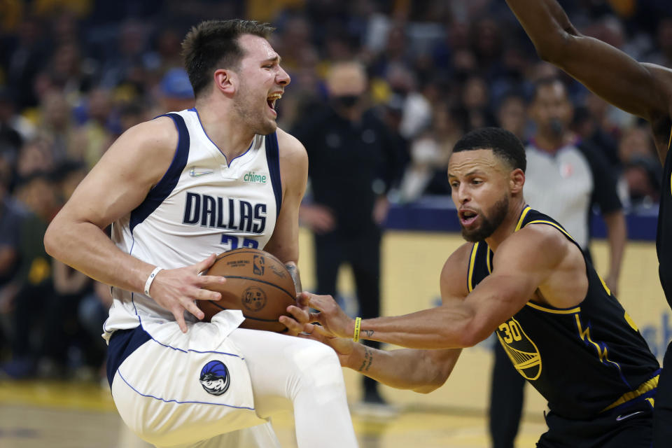 Dallas Mavericks guard Luka Doncic, left, is defended by Golden State Warriors guard Stephen Curry during the first half of Game 1 of the NBA basketball playoffs Western Conference finals in San Francisco, Wednesday, May 18, 2022. (AP Photo/Jed Jacobsohn)