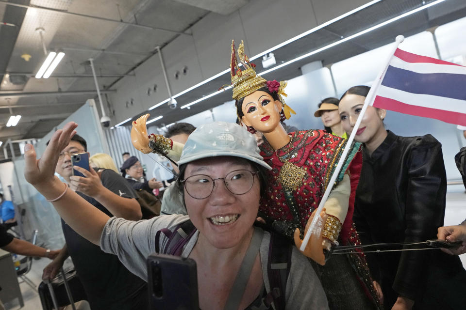 Chinese tourists dance with puppet as Chinese tourists are welcomed on the arrivals at Suvarnabhumi International Airport in Samut Prakarn province, Thailand, Monday, Sept. 25, 2023. Thailand's new government granting temporary visa-free entry to Chinese tourists, signaling that the recovery of the country's tourism industry is a top economic priority. (AP Photo/Sakchai Lalit)