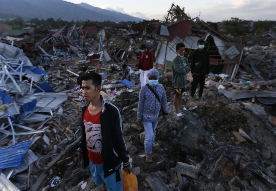 People survey the damage caused by Sept. 28 earthquake at Balaroa neighborhood in Palu, Central Sulawesi, Indonesia, Wednesday, Oct. 10, 2018. Indonesia's disaster agency said Wednesday that it only needs tents, water treatment units, generators and transport from other countries as it responds to the Sulawesi earthquake and tsunami that killed more than 2,000 people. (AP Photo/Dita Alangkara)