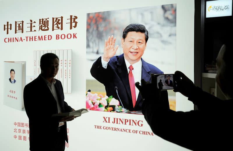 FILE PHOTO: A man poses for pictures at a booth of China's President Xi Jinping books displayed at the China International Import Expo in Shanghai