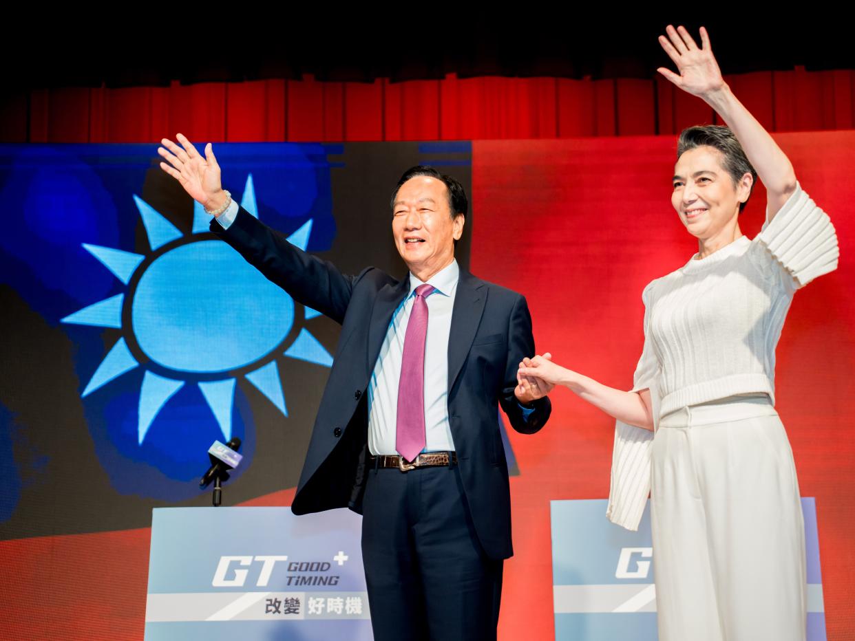 Terry Gou (left) and Tammy Lai (right) waving in front of a Taiwan flag.