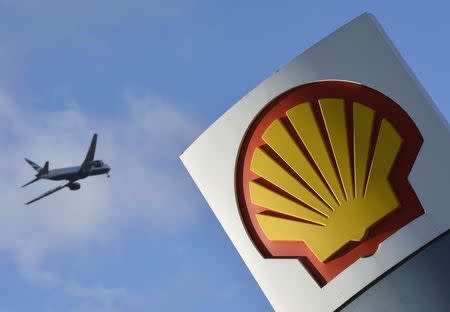A passenger plane flies over a Shell logo at a petrol station in west London, January 29, 2015. REUTERS/Toby Melville