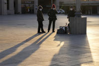 Residents wearing masks chat on an empty plaza outside the train station in Beijing, Thursday, Dec. 8, 2022. In a move that caught many by surprise, China announced a potentially major easing of its rigid "zero-COVID" restrictions, without formally abandoning the policy altogether. (AP Photo/Ng Han Guan)