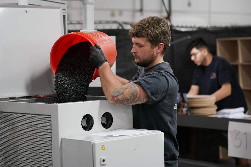 Thane Adolf dumps black vinyl pellets into a machine that will form the pellets into hockey puck-shaped "biscuits' to make vinyl record albums at the United Record Pressing facility Thursday, June 23, 2022, in Nashville, Tenn. (AP Photo/Mark Humphrey)