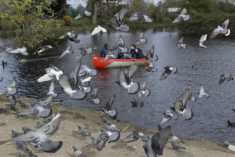 Pigeons fly as a family enjoy a boating lake in Finsbury Park as lockdown measures start to be relaxed in London, Friday, April 2, 2021. (AP Photo/Kirsty Wigglesworth)