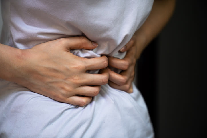 Close-up of a person gripping their abdomen, suggesting discomfort or pain