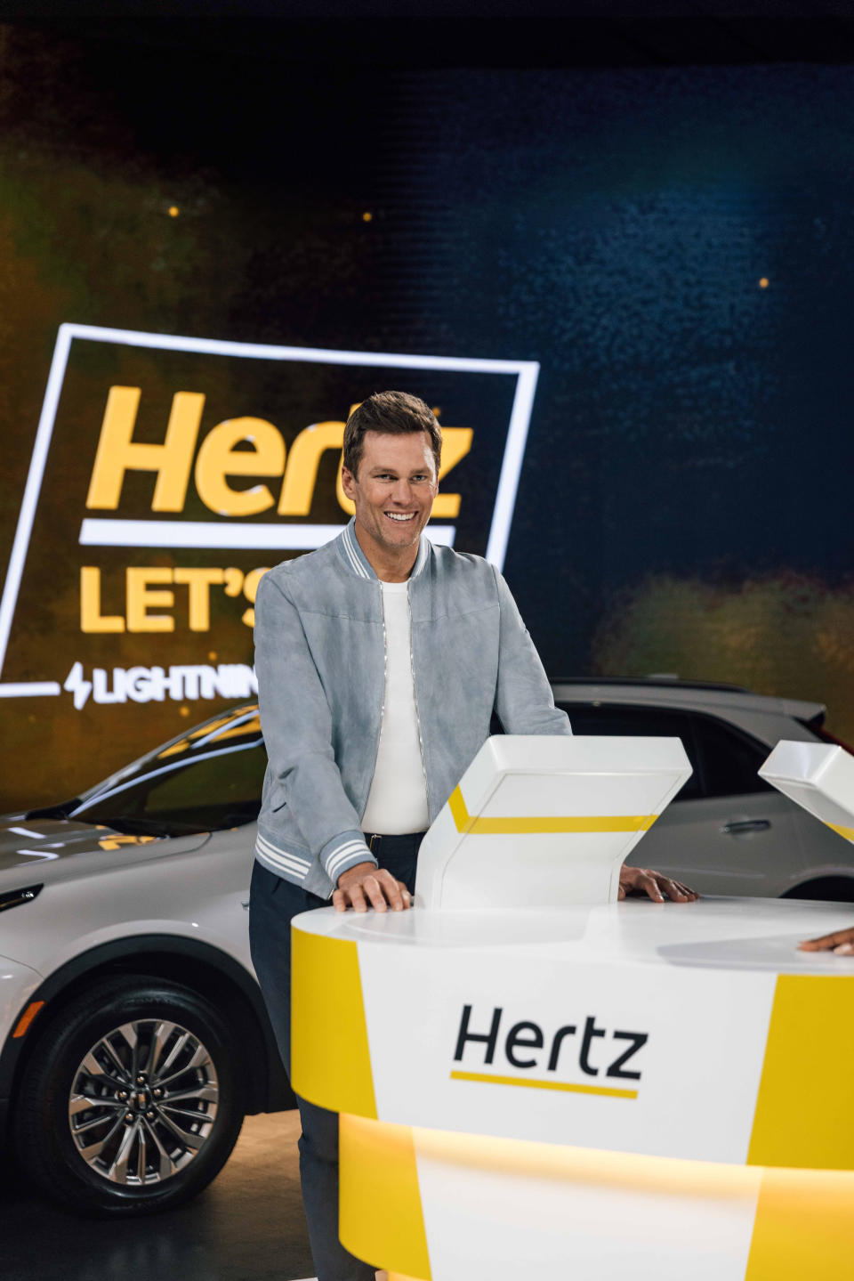 Tom Brady smiles on the set of a new Hertz campaign.