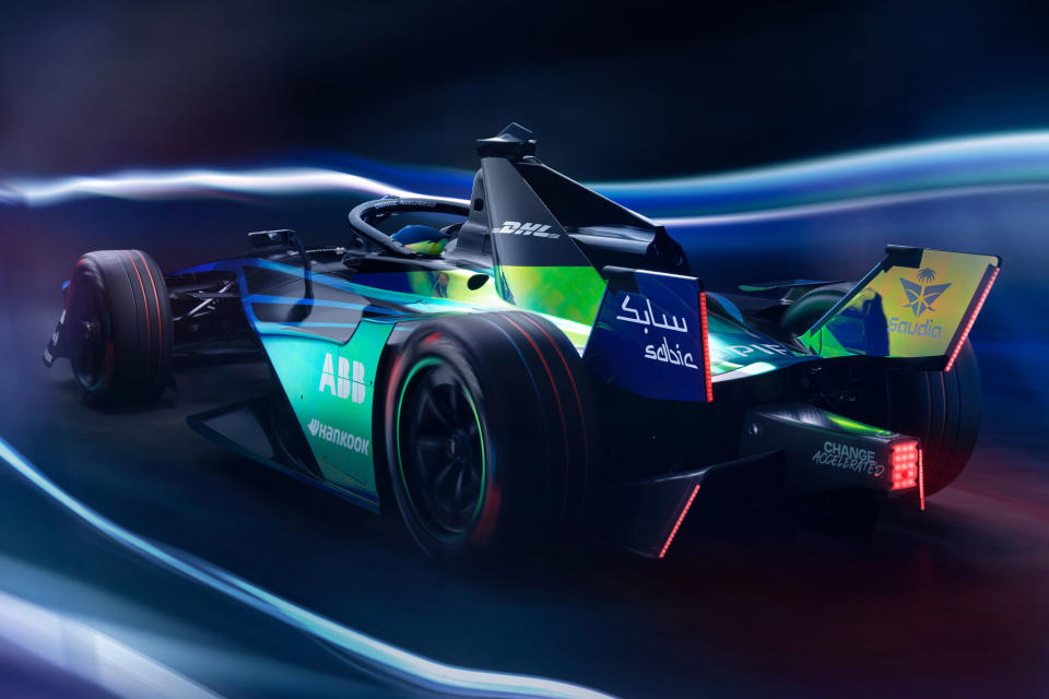 The Formula E Gen3 Evo drives away from the camera, blurred lights on either side.