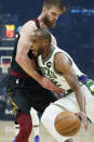Milwaukee Bucks' Khris Middleton, front, drives against Cleveland Cavaliers' Dean Wade in the first half of an NBA basketball game, Wednesday, Jan. 26, 2022, in Cleveland. (AP Photo/Tony Dejak)