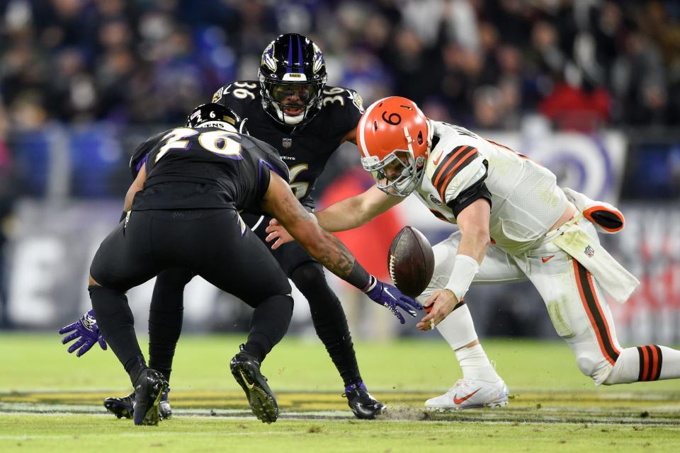 Browns quarterback Baker Mayfield fumbles the ball and Ravens safety Geno Stone (26) and safety Chuck Clark (36) try to recover the fumble during the first half of the Browns' 16-10 loss Sunday night in Baltimore. [Gail Burton/Associated Press]