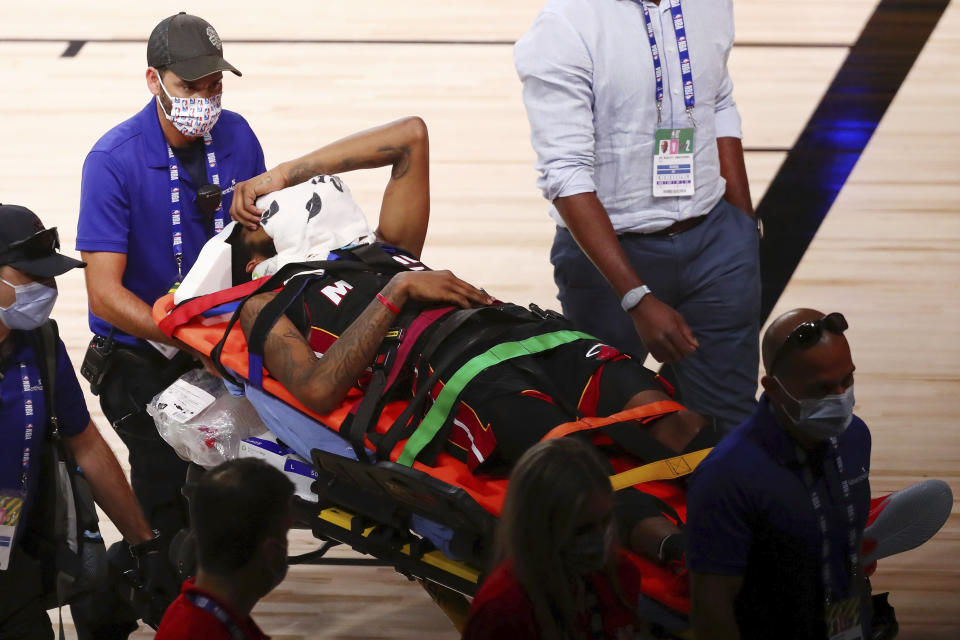 Miami Heat forward Derrick Jones Jr. (5) covers his face with a towel while he is taken off the court by medical personnel after colliding with Indiana Pacers center Goga Bitadze (not pictured) during the second half of an NBA basketball game Friday, Aug. 14, 2020, in Lake Buena Vista, Fla. (Kim Klement/Pool Photo via AP)