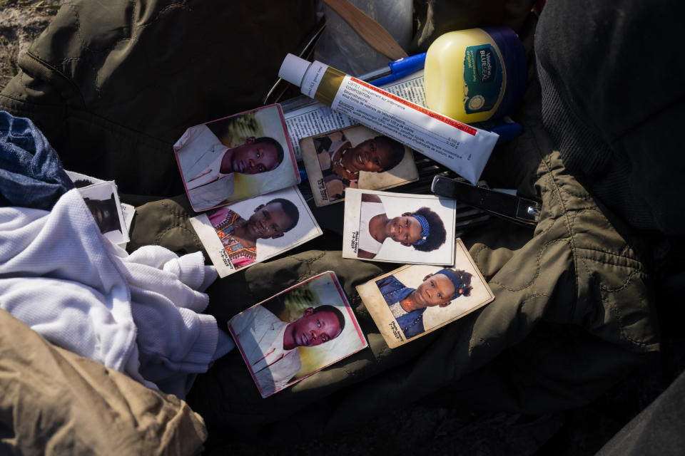 Personal belongings, including pictures of relatives, are piled next to a water pump as a migrant cleans himself near a makeshift migrant camp close to Dunkirk in northwest France on Sunday, May 19, 2024. (AP Photo/Bernat Armangue)