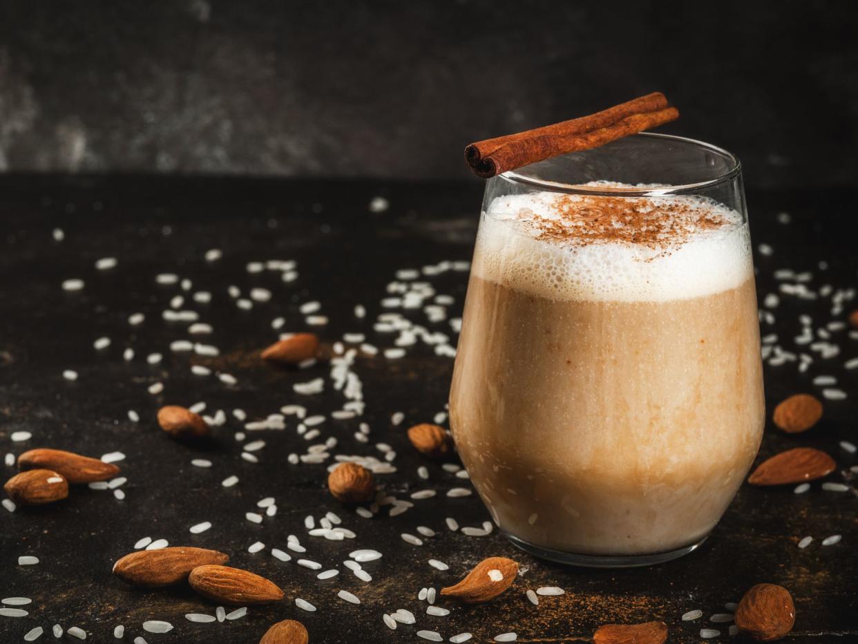 raditional Mexican drink Horchata Latte - coffee mixed with Horchata, a cocktail of almonds, rice vanilla and cinnamon. On a black concrete table, with ingredients.