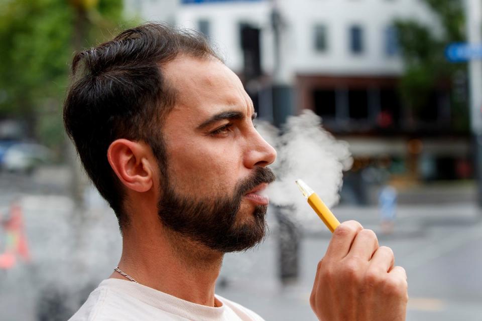 Vaping by a man in a street in Auckland, New Zealand on 9 December 2021 (AP)