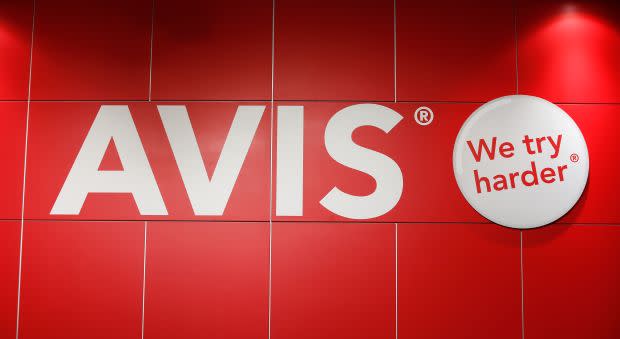 The Avis rental car company is pictured on a red wall with the phrase "We Try Harder."