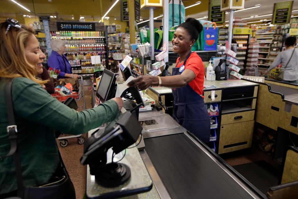 In this May 8, 2018, photo, Nadine Vixama, who emigrated from Haiti eight years ago, works as a cashier at a Whole Foods in Cambridge, Mass.