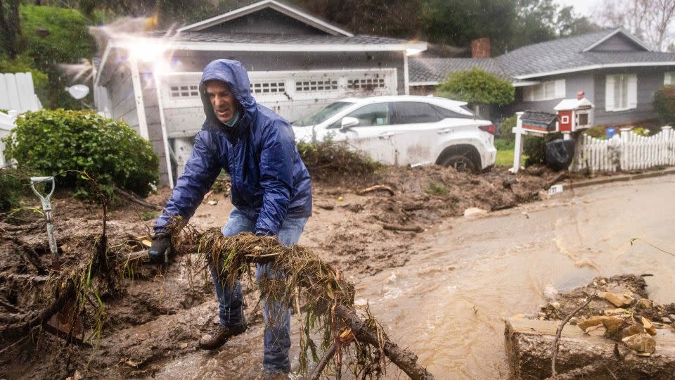 Jeffrey Raines clears debris from a mudslide at his parent's home Monday in Los Angeles. - Ethan Swope/AP