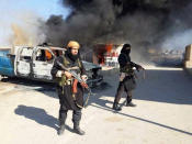 FILE - This undated file image posted on a militant website on Jan. 4, 2014, which is consistent with other AP reporting, shows Shakir Waheib, a senior member of the al-Qaida-linked Islamic State of Iraq and the Levant (ISIL), left, next to a burning police vehicle in Iraq's Anbar Province. The ISIL led by Abu Bakr al-Baghdadi is the main driver of destabilizing violence in Iraq and until recently was the main al-Qaida affiliate there. Al-Qaida’s general command formally disavowed the group this week, saying it "is not responsible for its actions." (AP Photo via militant website, File)
