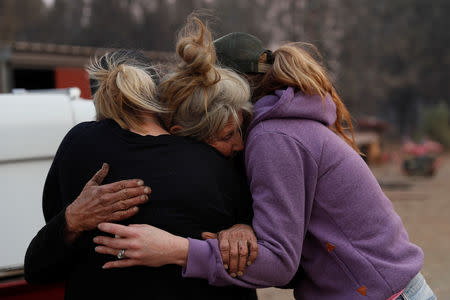 Cathy Fallon (C) who stayed behind to tend to her horses during the Camp Fire, embraces Shawna De Long (L) and April Smith who brought supplies for the horses in Paradise, California, U.S. November 11, 2018. REUTERS/Stephen Lam