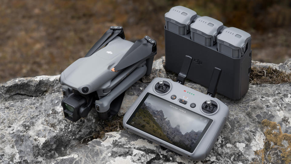 DJI Air 3 drone in folded position on a rock, alongside battery charging hub