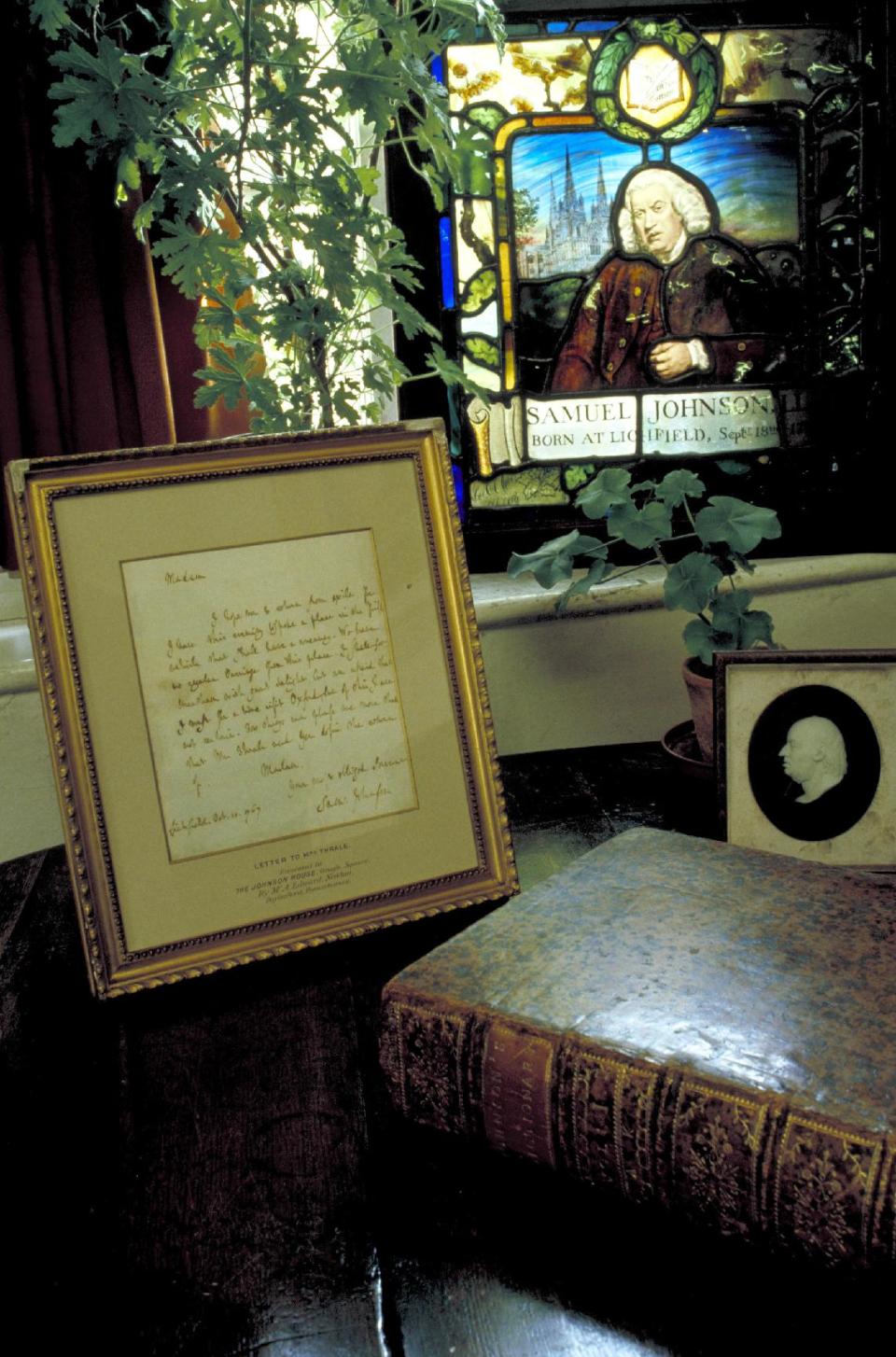 This March 17, 2009 photo released by VisitBritain shows shows a letter written by Samuel Johnson and a copy of the dictionary he wrote, which was published in 1755, beneath a stained glass plaque at Dr. Johnson’s House, a small museum in the 300-year-old townhouse where he lived in London. The house is a good destination for visitors on a literary tour of London. (AP Photo/VisitBritain)