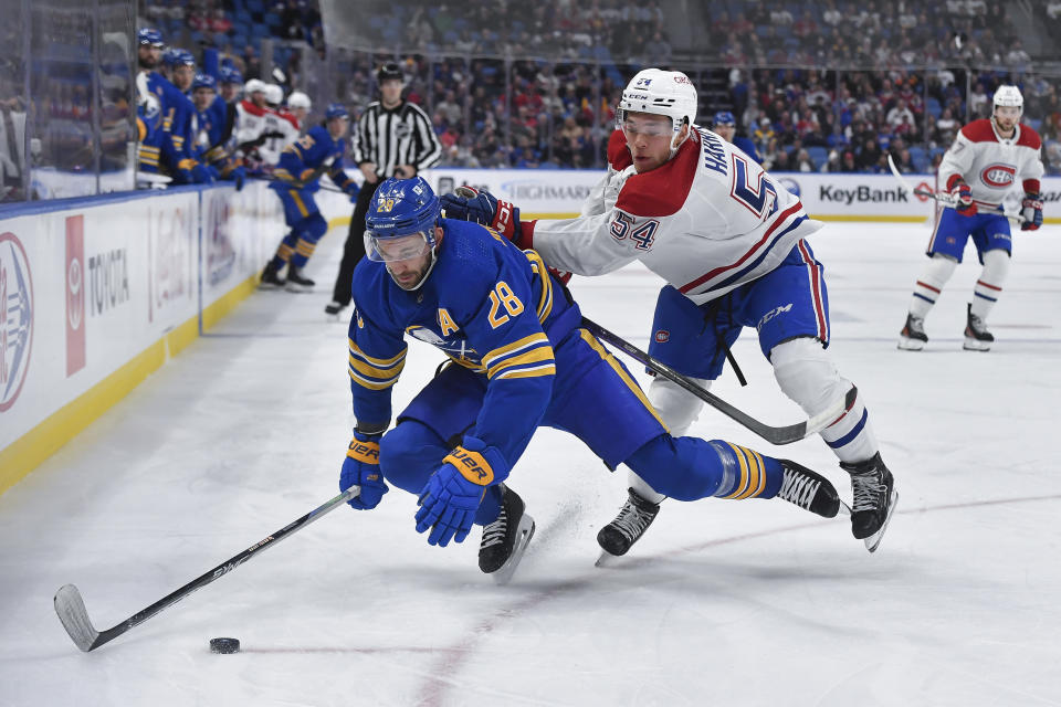 Buffalo Sabres left wing Zemgus Girgensons, left, takes a hit from Montreal Canadiens defensemen Jordan Harris during the second period of an NHL hockey game in Buffalo, N.Y., Monday, Oct. 23, 2023. (AP Photo/Adrian Kraus)