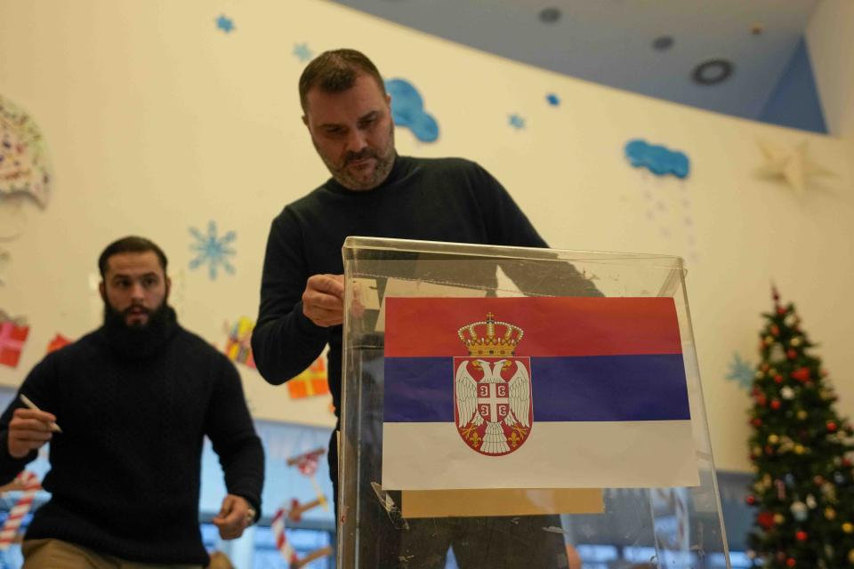 Members of the electoral commission prepare ballot box at a polling station for a parliamentary and local election in Belgrade, Serbia, Sunday, Dec. 17, 2023. The vote in Serbia pits Serbian President Aleksandar Vucic's governing Serbian Progressive Party, or SNS, against a pro-Western opposition coalition which is trying to undermine the firm grip on power the populists have maintained since 2012. (AP Photo/Darko Vojinovic)