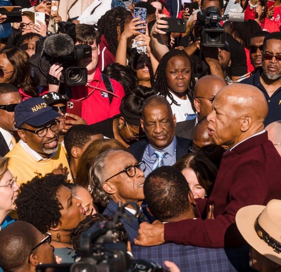 Derrick Johnson, president of the NAACP, in the blue cap, listens to Rep. John Lewis, D-Ga., address a crowd March 1 on the Edmund Pettus Bridge in Selma, Ala.