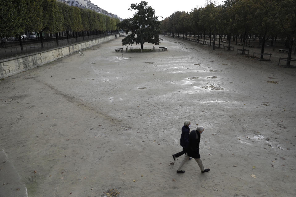 People walk in the empty Tuileries gardens Wednesday, Oct.14, 2020 in Paris. French President Emmanuel Macron is giving a nationally televised interview Wednesday night to speak about the virus, his first in months. French media reports say Macron will also step up efforts on social media to press the need for virus protections among young people. (AP Photo/Lewis Joly)