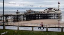 FILE PHOTO: A woman pulls her suitcase past the North Pier in Blackpool, Britain May 16, 2017. REUTERS/Phil Noble/File Photo