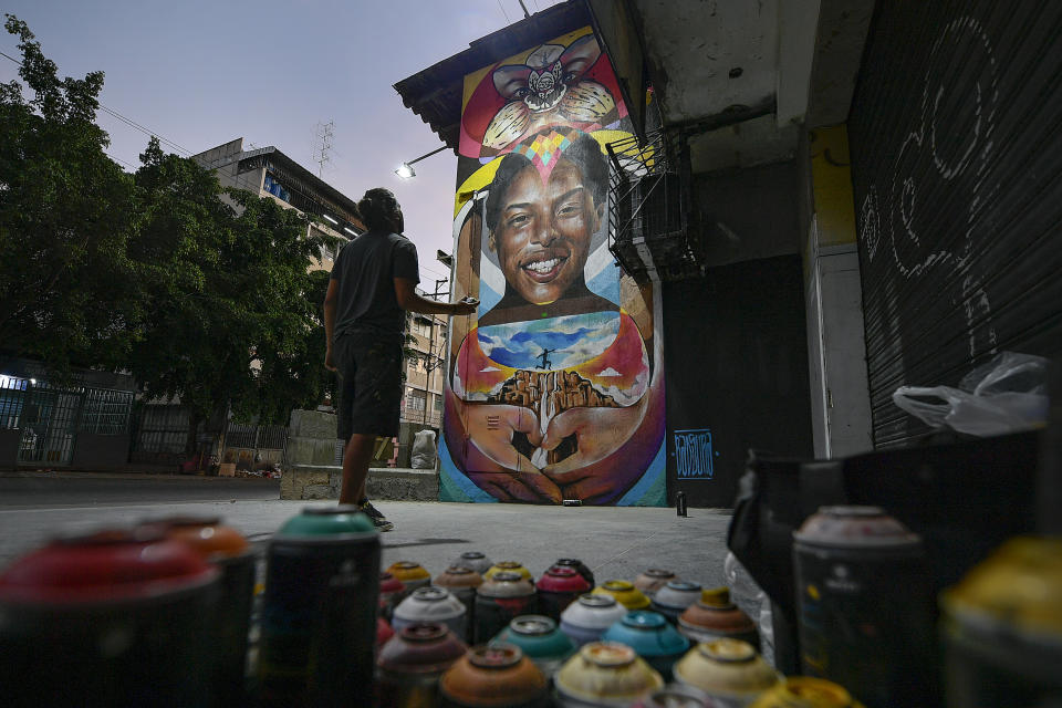 Street artist Wolfgang Salazar studies his mural honoring Venezuelan athlete Yulimar Rojas as he adds finishing touches, in the Boleita neighborhood of Caracas, Venezuela, Monday, Jan. 11, 2021. Salazar has gained increasing fame for his spray-painted murals of Venezuelans at a time when the pandemic and economic hardship weigh upon his fellow citizens. “I want people to smile for a moment,” said the 30-year-old Salazar. “I want them to go home with a different kind of story to tell.” (AP Photo/Matias Delacroix)