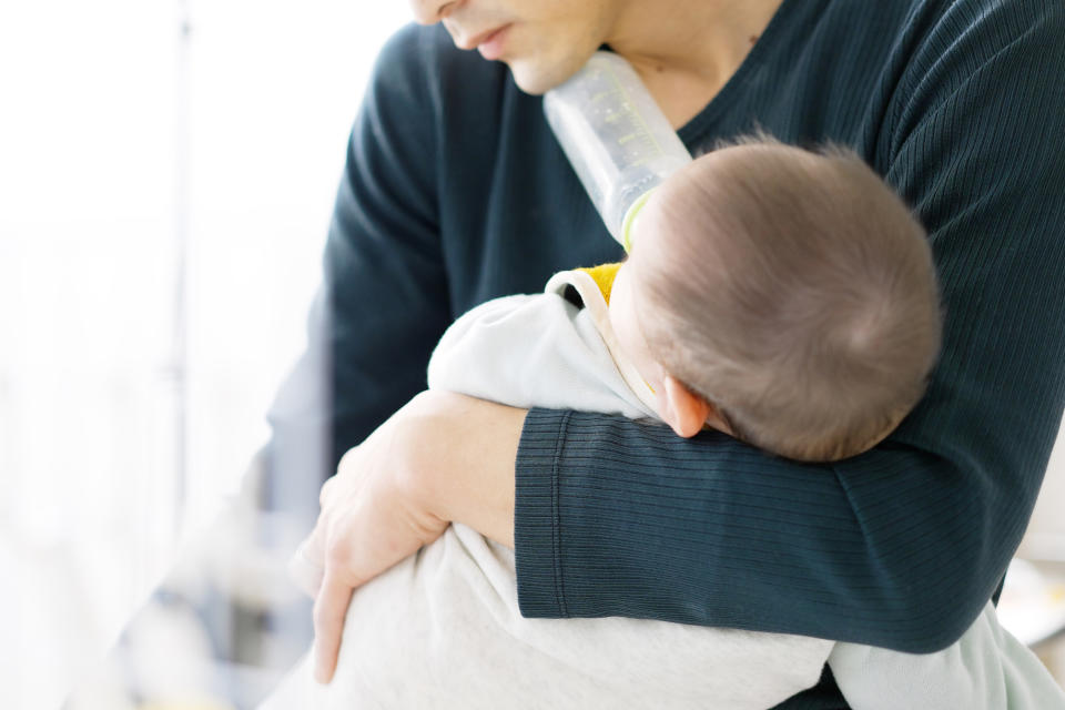 Person feeding a baby with a bottle while holding the child close to their chest