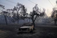 A burned car is seen after a wildfire in Varibobi area, northern Athens, Greece, Wednesday, Aug. 4, 2021. More than 500 firefighters struggled through the night to contain a large forest blaze on the outskirts of Athens, which raced into residential areas Tuesday, forcing thousands to flee. It was the worst of 81 wildfires that broke out in Greece over the past 24 hours, amid one of the country's most intense heatwaves in decades. (AP Photo/Thanassis Stavrakis)