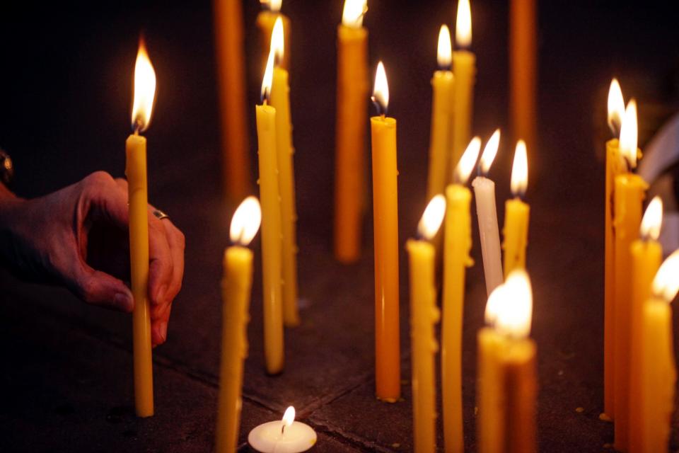 <p>A woman lights a candle during a vigil in Bangkok. (Dario Pignatelli/Getty Images) </p>