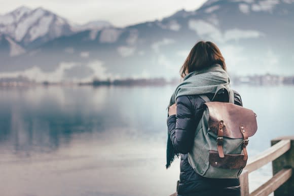 A woman looking at a lake with a mountain in the background.