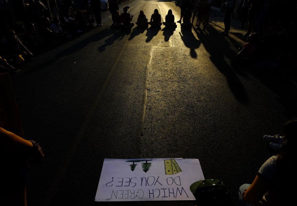 People block the road as they sit outside of the Brazilian Embassy during a protest in Nicosia, Cyprus, Friday, Aug. 23, 2019, Some people gathering outside of the Brazilian embassy to call on Brazil's President Jair Bolsonaro to act to protect the Amazon rainforest. The European Union is throwing its weight behind French President Emmanuel Macron's call to put the Amazon fires on the agenda of this weekend's G-7 summit of world leaders in France. (AP Photo/Petros Karadjias)