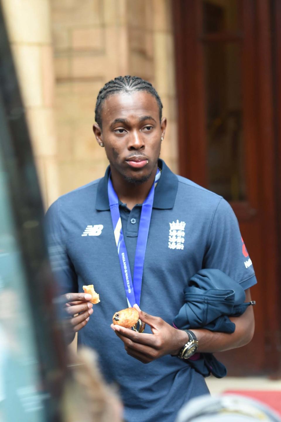 Jofra Archer tucks into a pastry as he follows teammates onto the bus (Jeremy Selwyn)