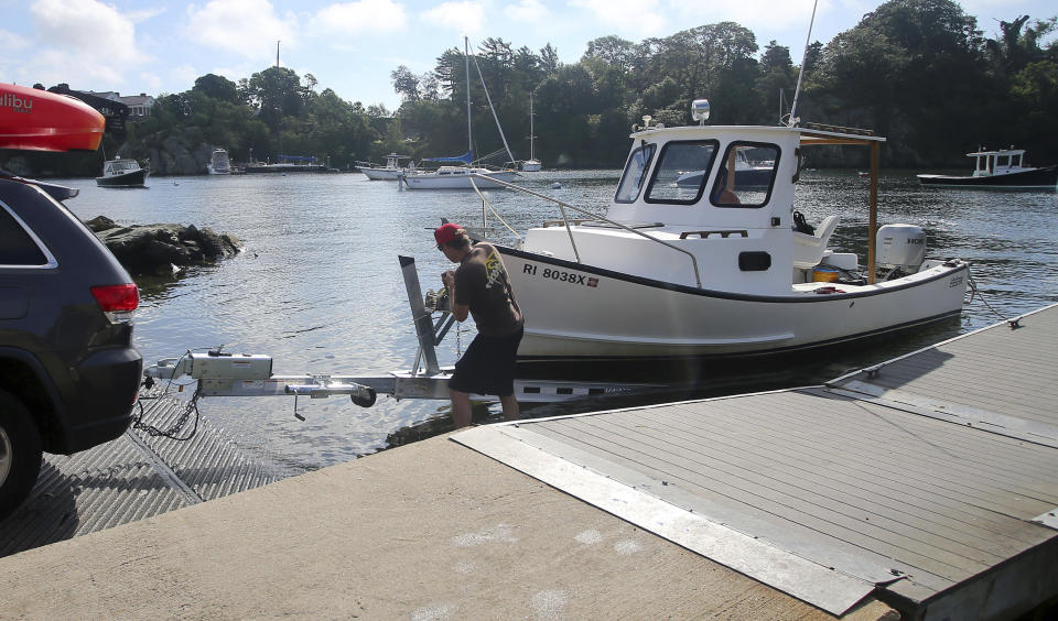 Carson Turowski, center, secures his boat as his wife Lindsey drives it onto the trailer as they remove it before pending bad weather Saturday, Aug. 21, 2021, in Newport, R.I. New Englanders, bracing for their first direct hit by a hurricane in 30 years, are taking precautions as Tropical Storm Henri barrels toward the southern New England coast. (AP Photo/Stew Milne)